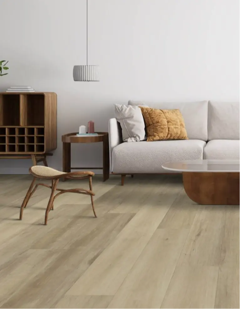 Living room with a curved tan velvet sofa, potted plant, and beige carpet flooring.